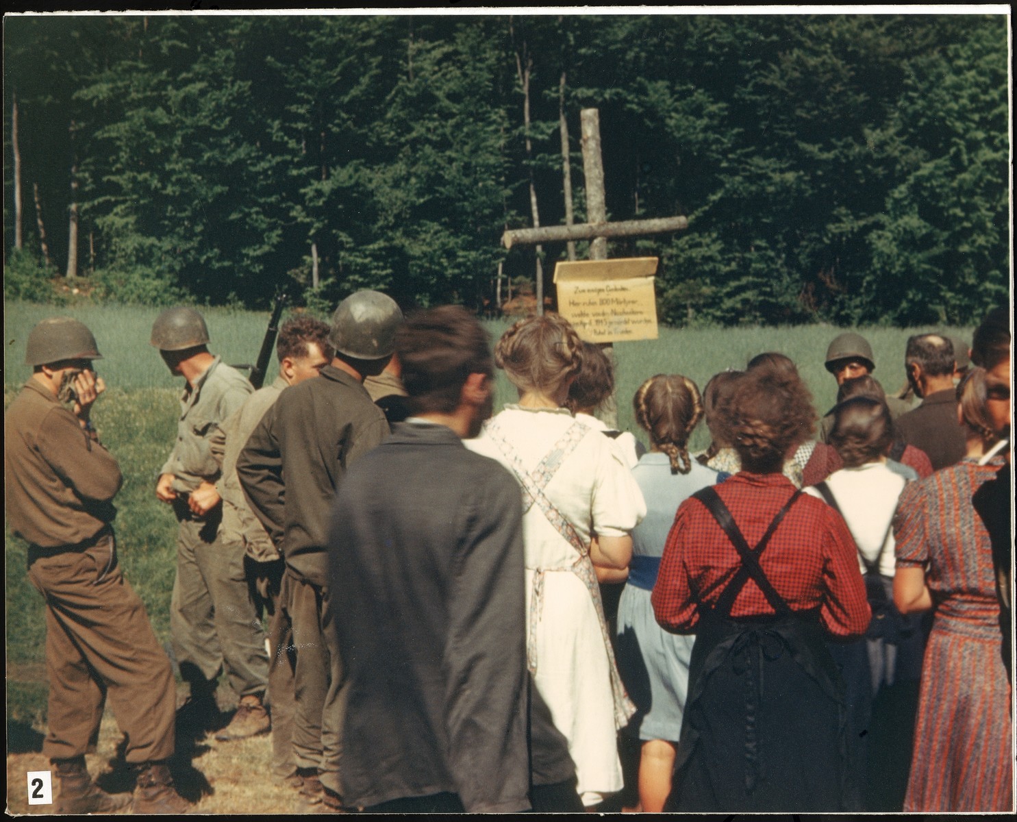 Under the direction of American soldiers, German civilians are forced to read the sign erected by the U.S. Army to mark the site of the Nammering atrocity.