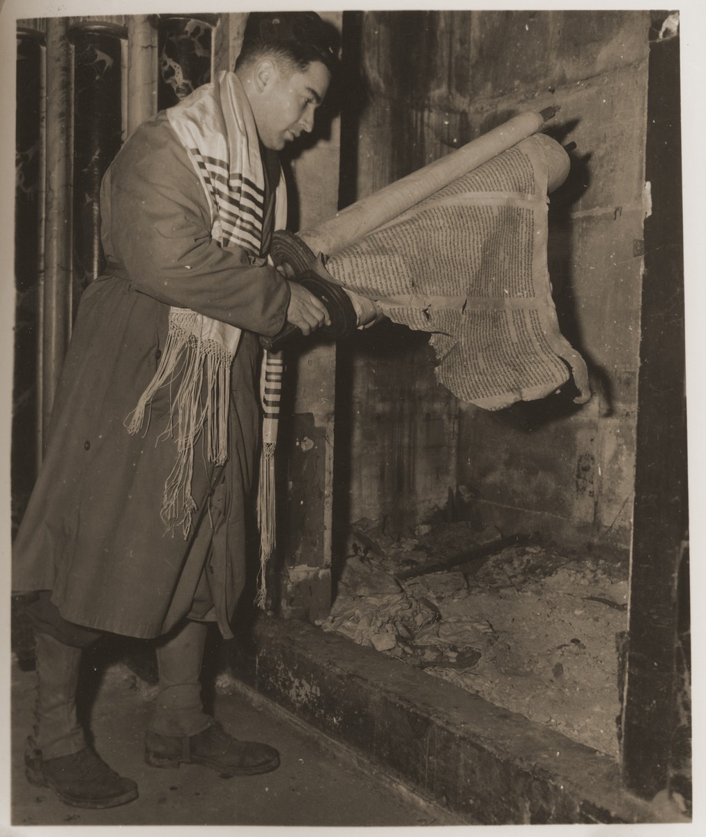 U.S. Army chaplain Herman Dicker from Brooklyn, N.Y., examines a damaged Torah scroll in the ark of the destroyed synagogue in Metz.
