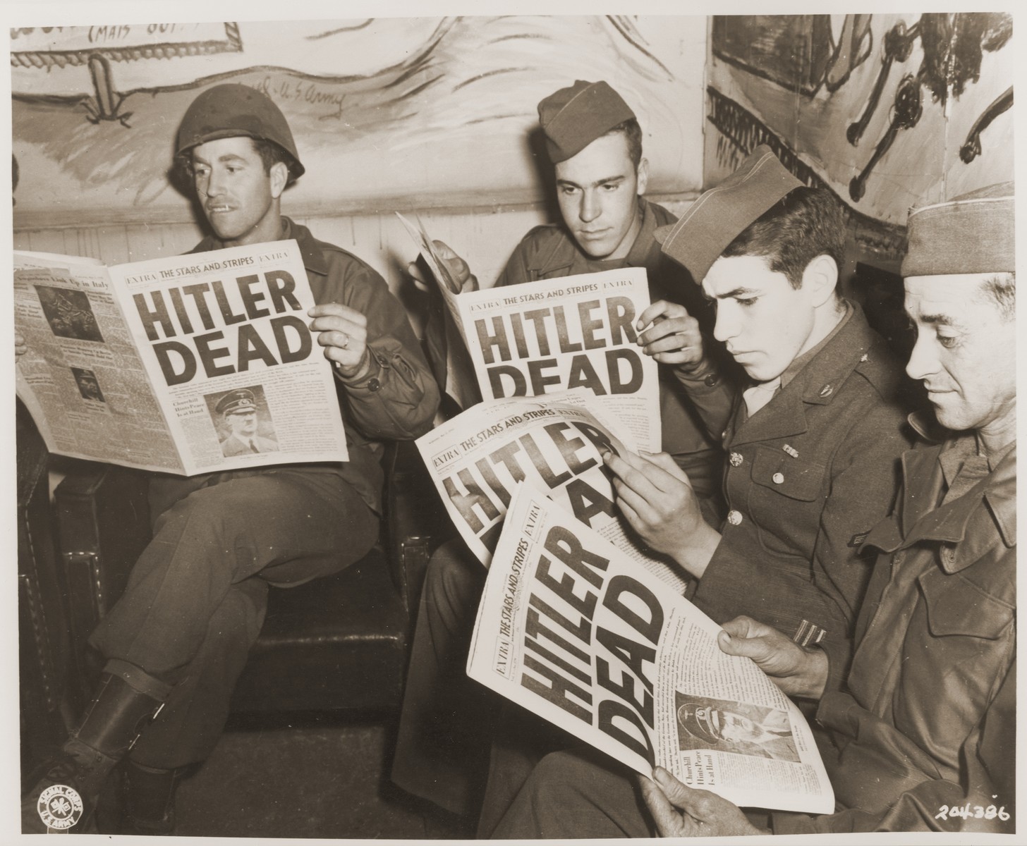 American soldiers read of Hitler's death in an "extra" edition of "Stars and Stripes."  Pictured left to right: Pfc. Leonard A. Davis, Pfc. Richard Webster, Pfc. Julian Bellavance, and Pfc. Lex Hall.