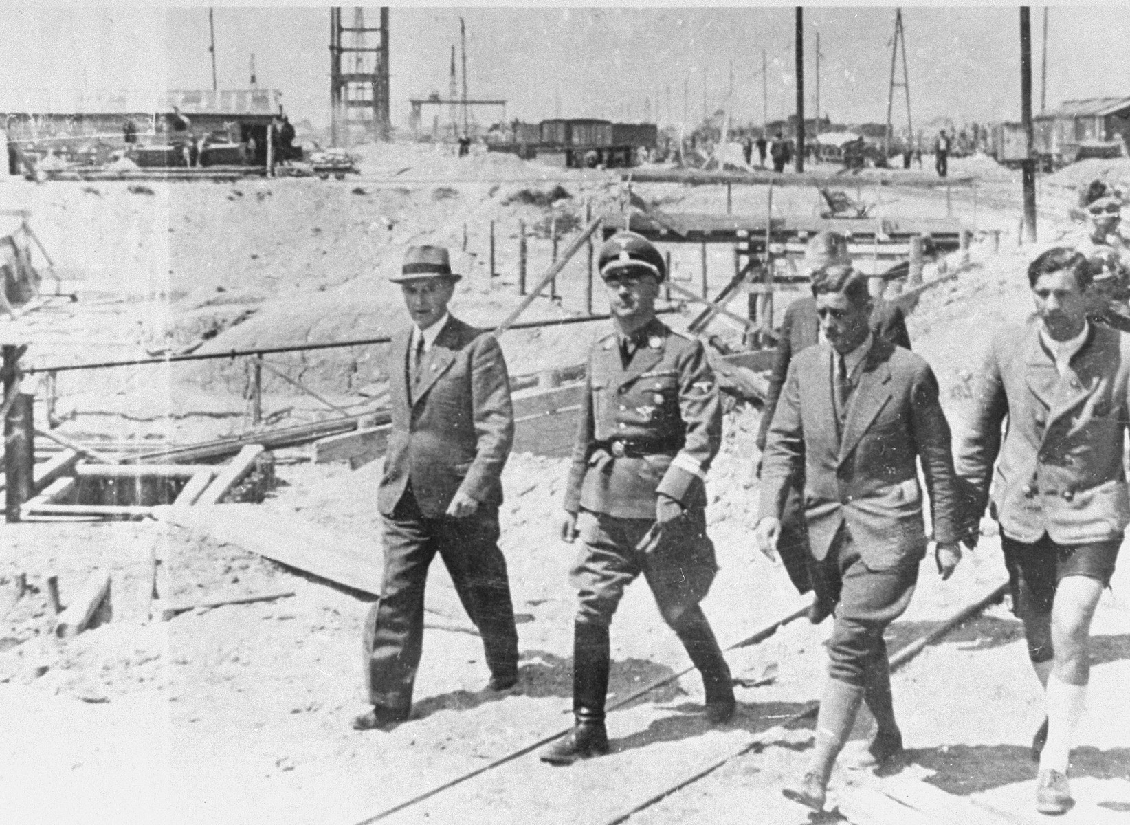 Reichsfuehrer SS Heinrich Himmler tours the Monowitz-Buna building site in the company of Max Faust (first on the left). 

Faust, who was an IG Farben engineer, was the head of building operations at Monowitz-Buna.