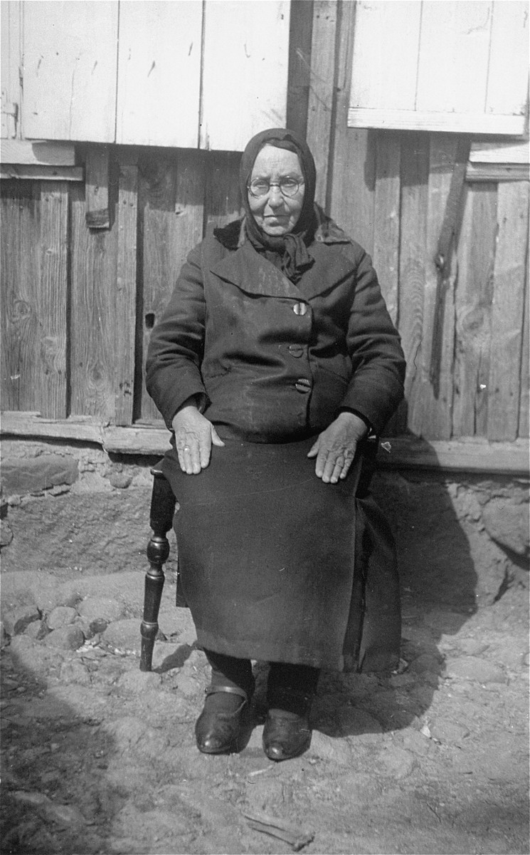 Portrait of an elderly woman from the Olchwanger family sitting in front of her home.