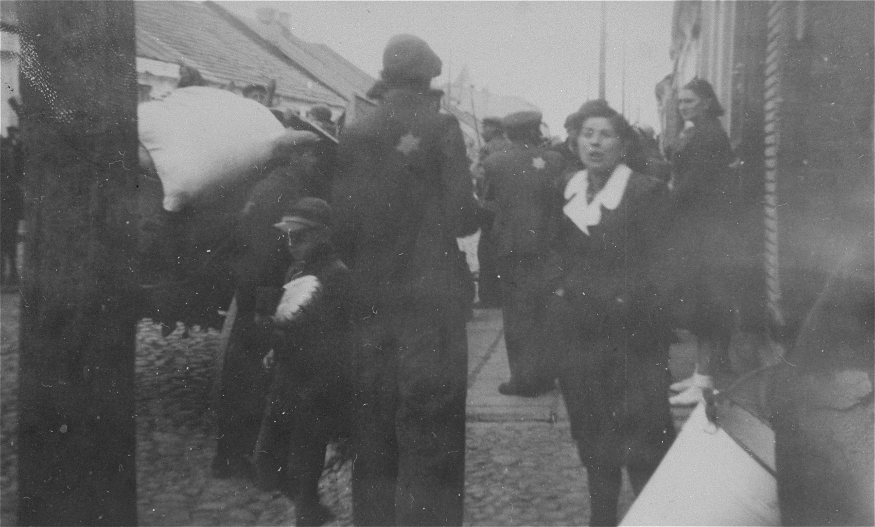 Jews stand on Pabianicka Street in Belchatow during a resettlement or deportation action.
