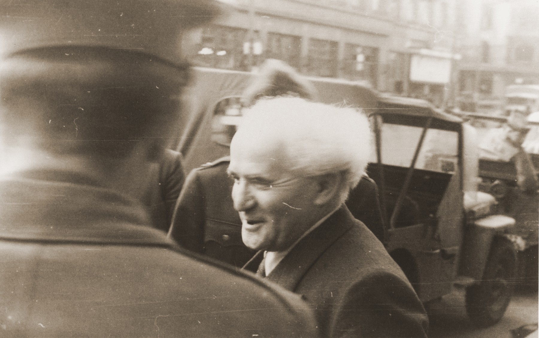 David Ben-Gurion is greeted by Chaim Hoffmann (with his back to the camera) and others during an official visit to the American zone of Germany.  

Ben-Gurion is on his way to the Babenhausen bei Aschaffenburg displaced persons camp near Frankfurt.