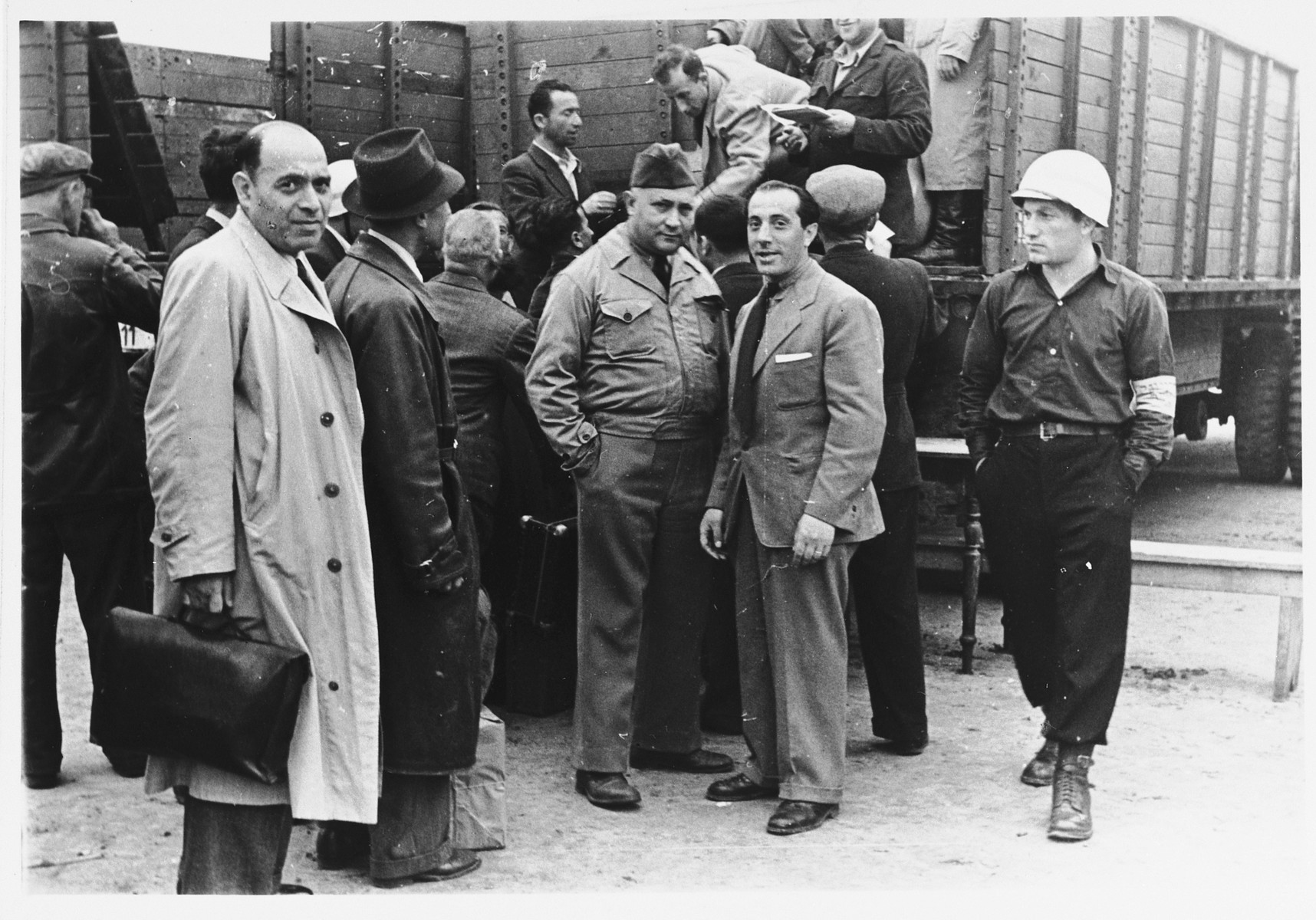 UNRRA camp director Harold Fishbein poses with other officials at the Schlachtensee displaced persons camp, where Jewish DPs are boarding large trucks.  

Harold Fishbein is standing in the center (third from the right).