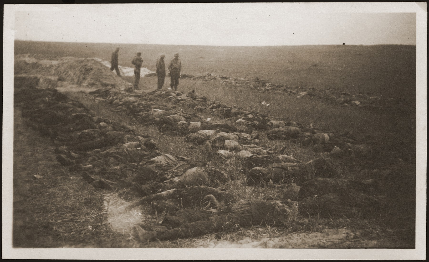American soldiers stand among the corpses of concentration camp prisoners killed by the SS in a barn just outside of Gardelegen, which have been laid out for burial.