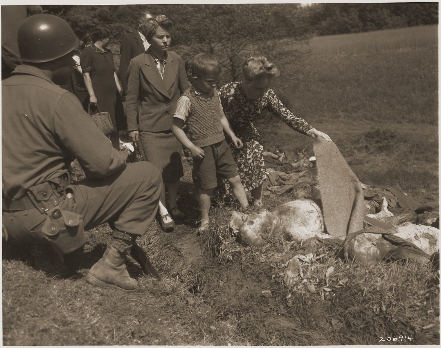 German civilians are forced to see the bodies of prisoners exhumed from a mass grave near Nammering.  

An African- American soldier observes the procession of German civilians.