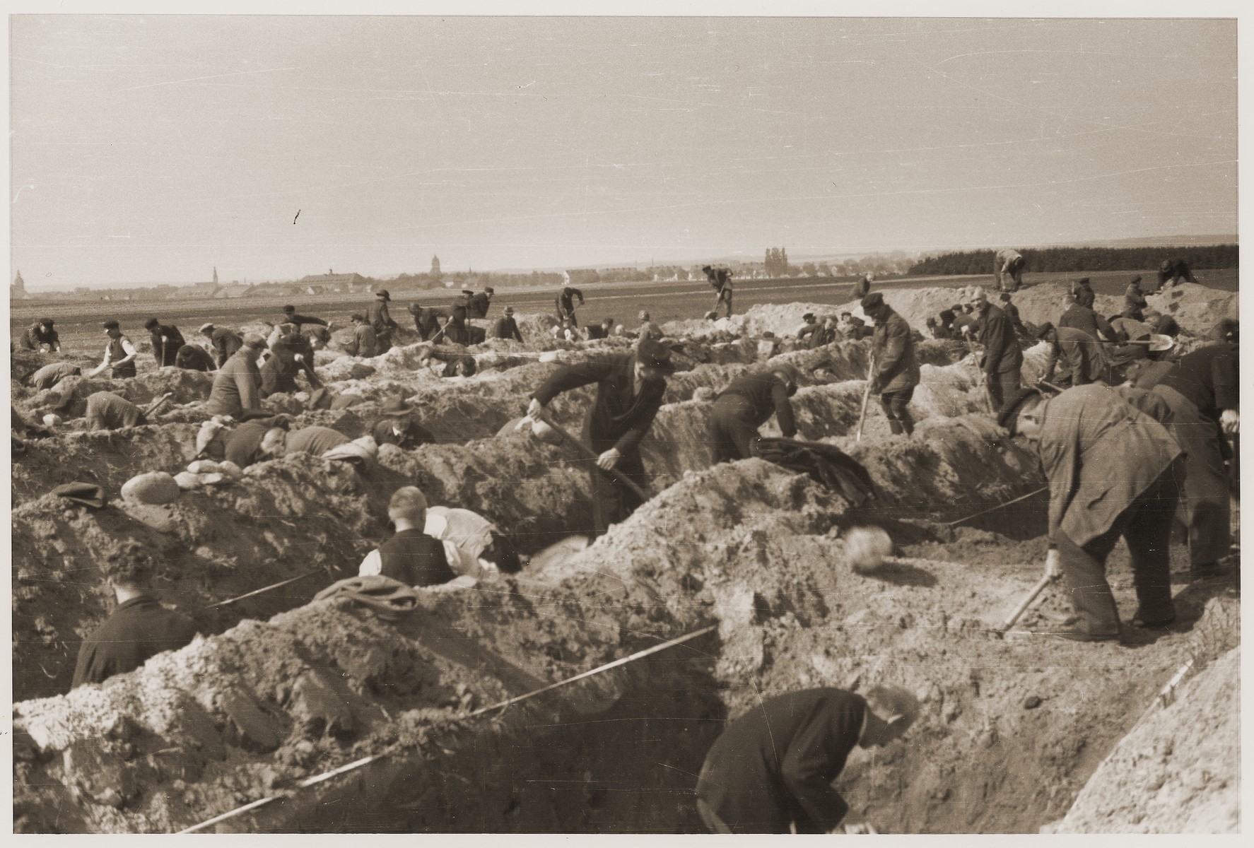 German civilians dig graves for the bodies of concentration camp prisoners killed by the SS in a barn just outside of Gardelegen.  The town of Gardelegen can be seen in the distance.