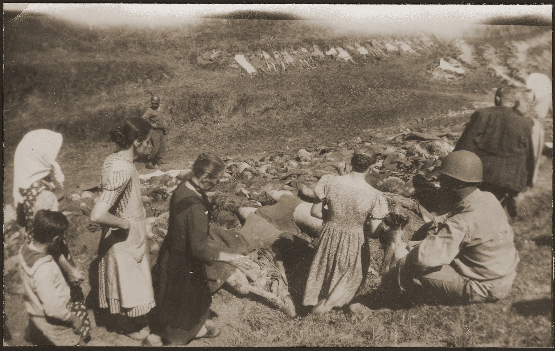 German civilians from Nammering are forced  by U. S. troops to look at the corpses exhumed from a mass grave near the town.