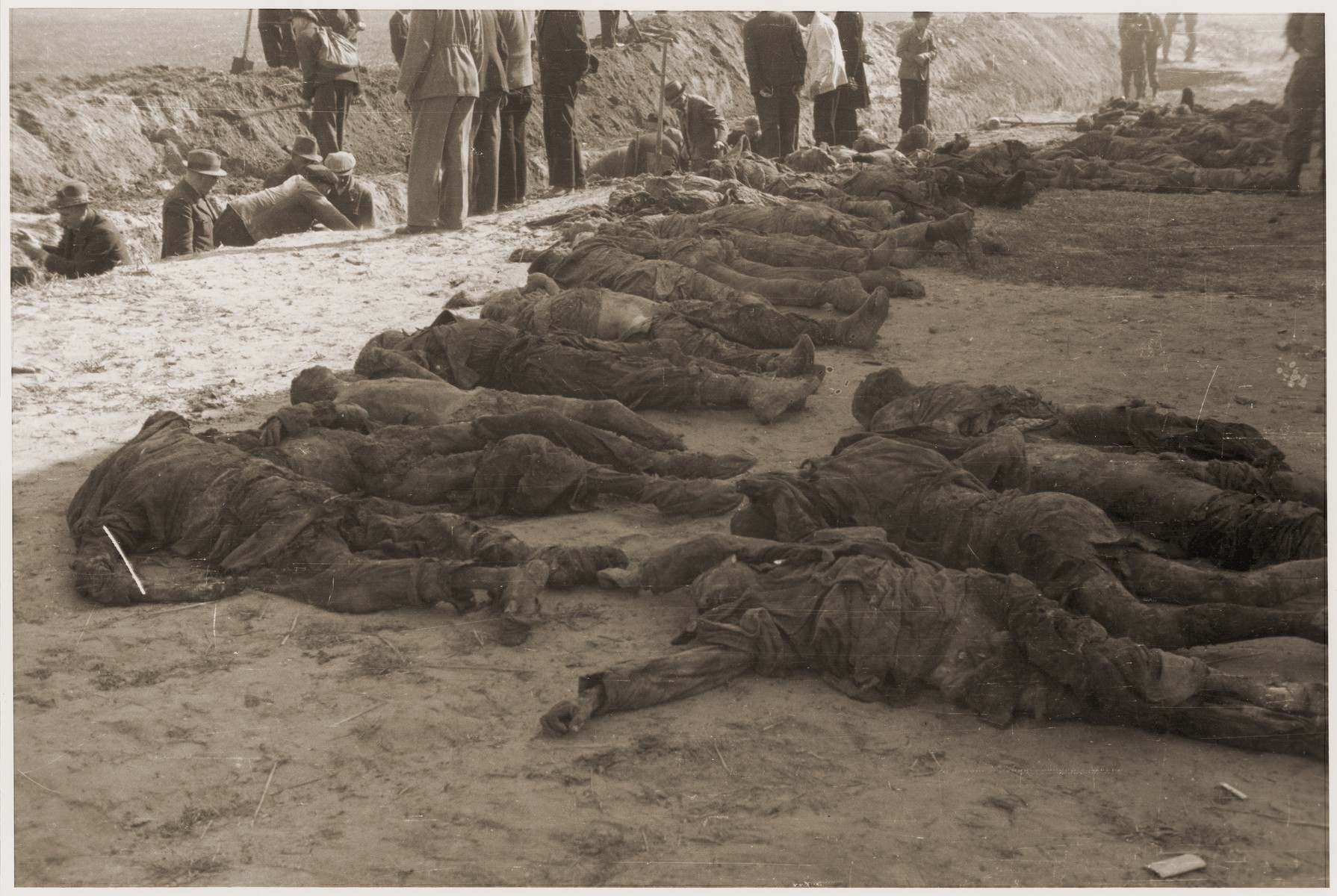 Under the supervision of American soldiers, German civilians exhume a mass grave containing the bodies of concentration camp prisoners killed by the SS in a barn just outside of Gardelegen.