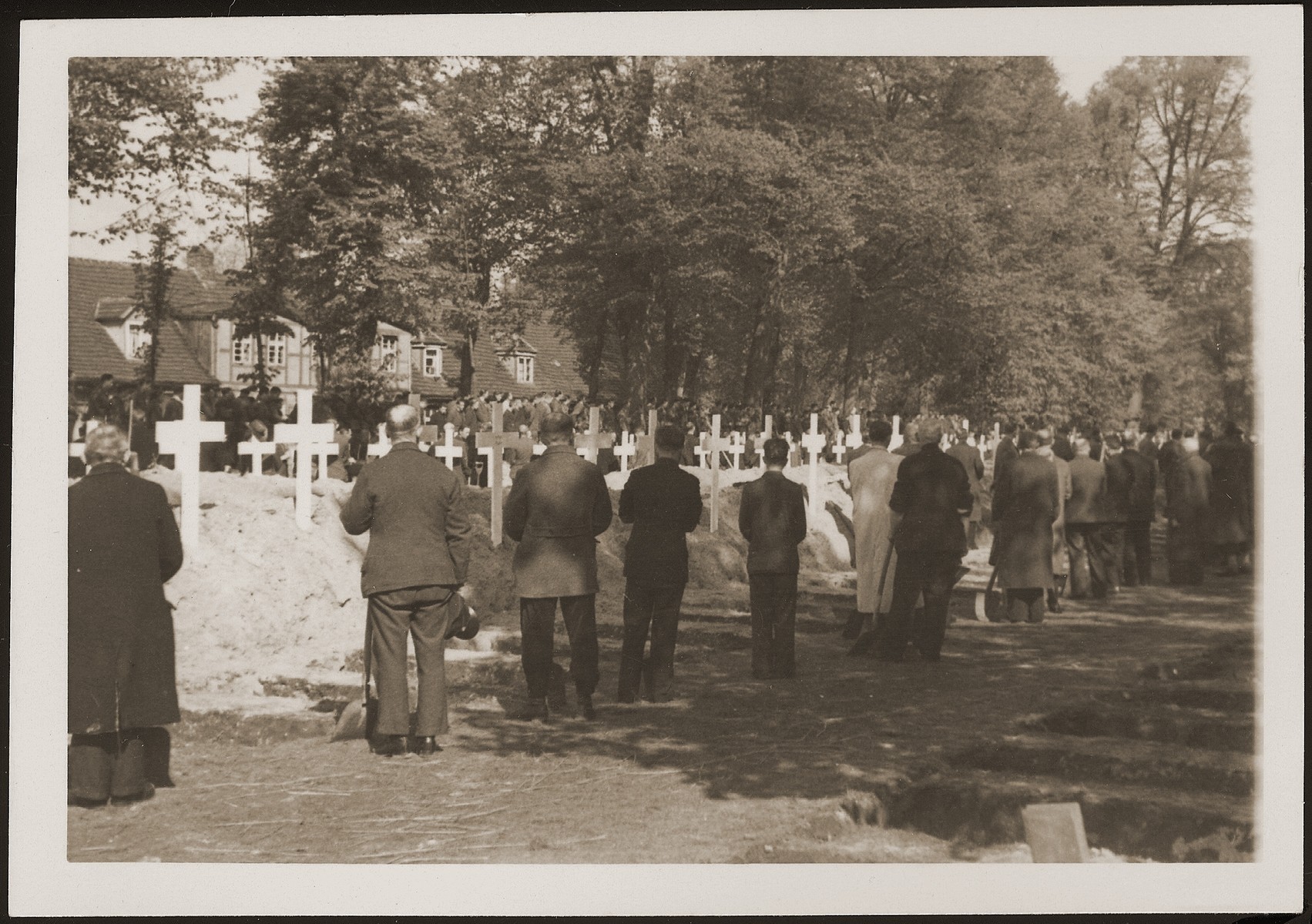 German civilians from Ludwigslust pause for a moment of silence at the mass funeral on the palace grounds of the Archduke of Mecklenburg, where they have been forced by U.S. troops to bury the bodies of prisoners killed in the Woebbelin concentration camp.