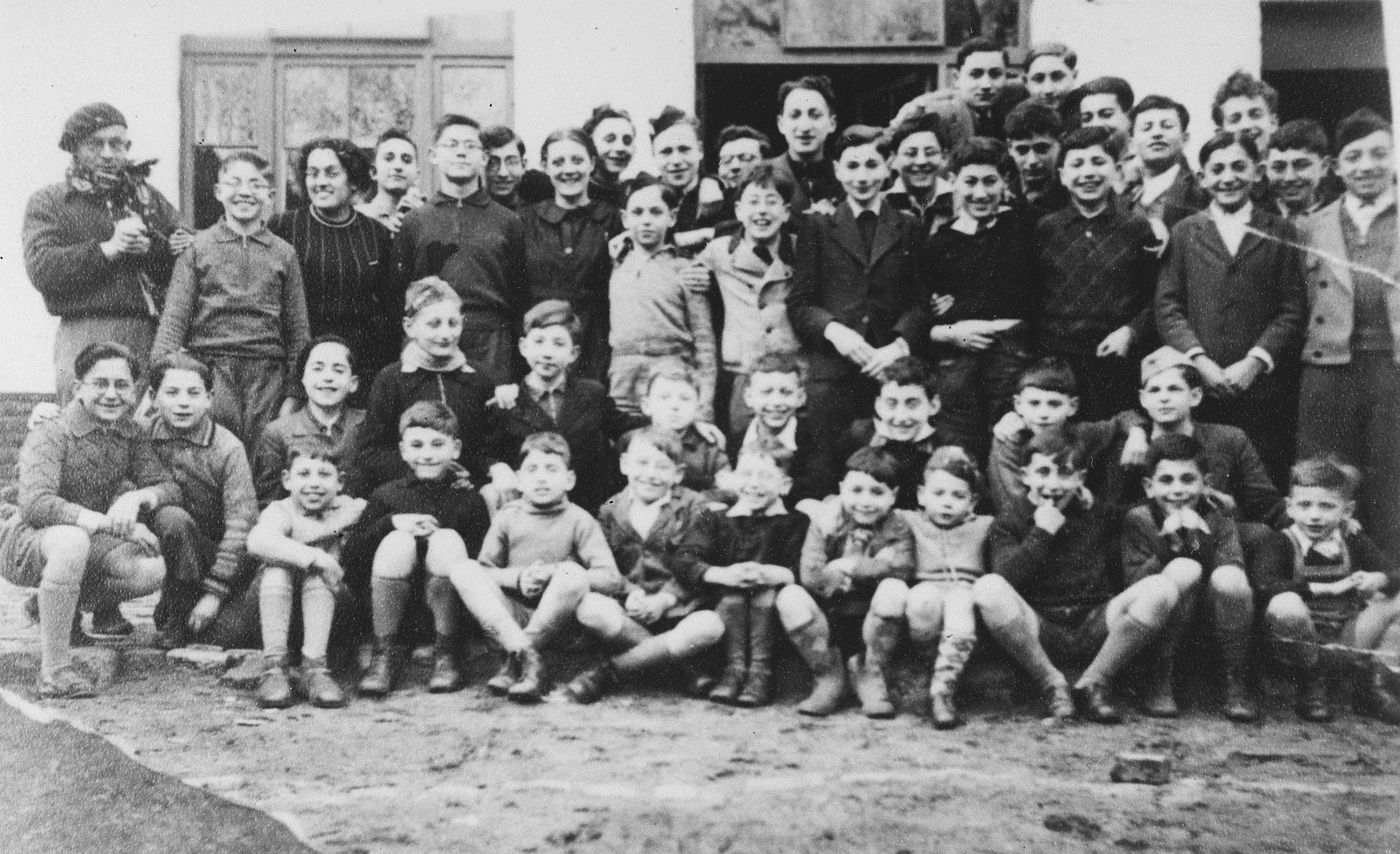 Group portrait of the children who came to Belgium from Germany and Austria on a Kindertransport outside the Speyer children's home at 128 rue Victor Rauter in Anderlecht.

Front row (left to right): Guy Haas, Georges Herz, Willy Wolpert (?), Alfred Eschwege, Fred Findling. Manfred Tidor, Henri Vos, Gerhard Eckmann, unknown, and Martin Findling.  Second row: Gerard Kwaczkowski. Manfred Vos, Egon Berlin, Rudi Oehlbaum, unknown, Bernard Eisler, unknown, Joseph Dortort, Max Krolik, and Klaus Sostheim.  Back row: Mr. Becker, Willy Grossmann, female counselor, Gerd Obersitzker, Leo Grossmann, Emile Dortort, Tante Lucienne DeWaay, unknown, Peter Salz, Edgar Chaim, Manfred Kamlet, unknown, Bertrand Elkan, Hans Garfunkel. Lucien Wolfgang. unknown, Henri Brunel. Werner Rindsberg, Jacques Roth, Norbert Stueckler, Kurt "Onze" Klein, and Norbert Winter.  Far back are Charles Blumenfeld, and Eddie Nussbaum.