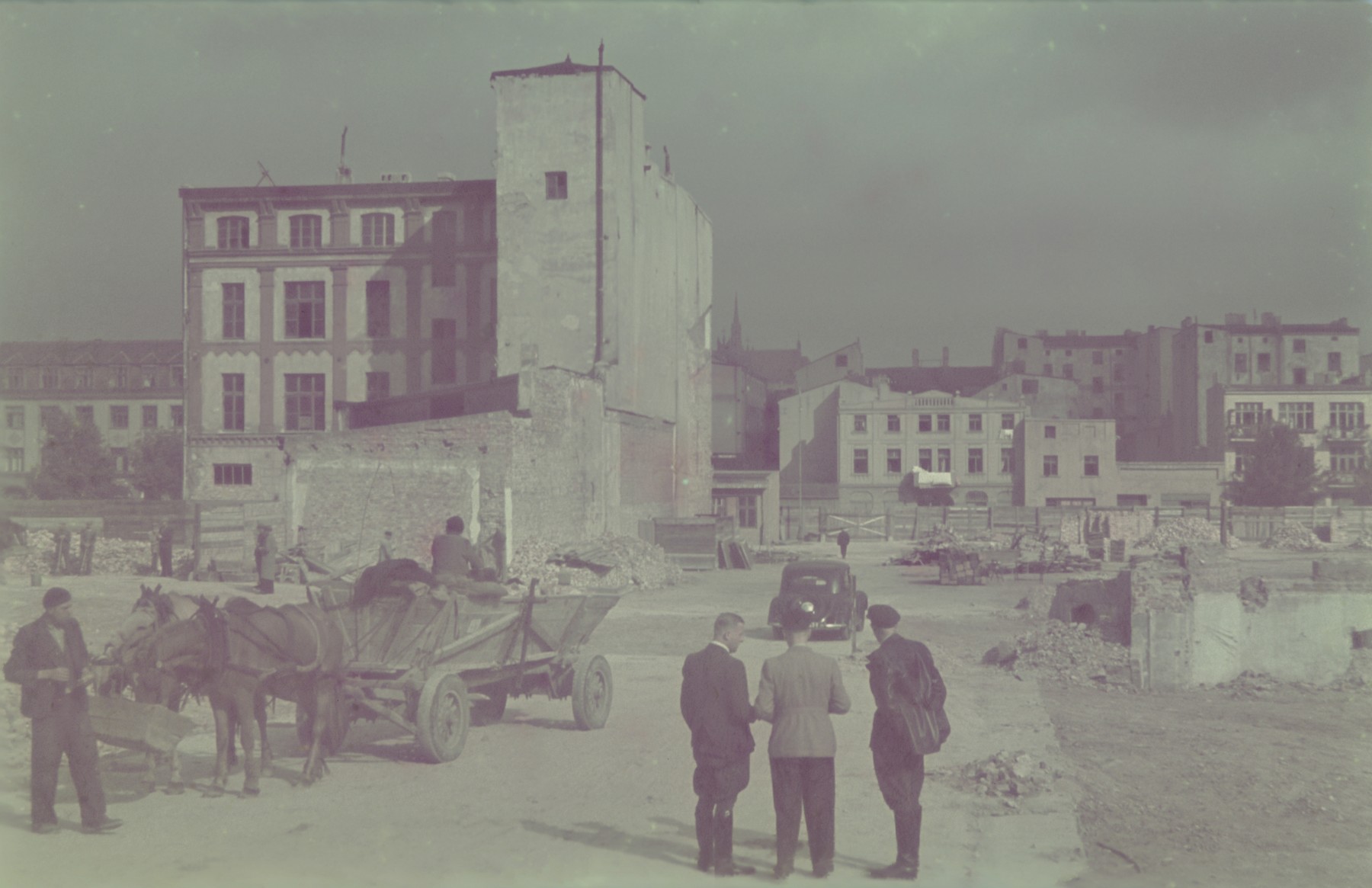 Hans Biebow and two other men survey a partially destroyed street in the Lodz ghetto.

Original German caption: "...aktion" #171 (number 160 was crossed out)