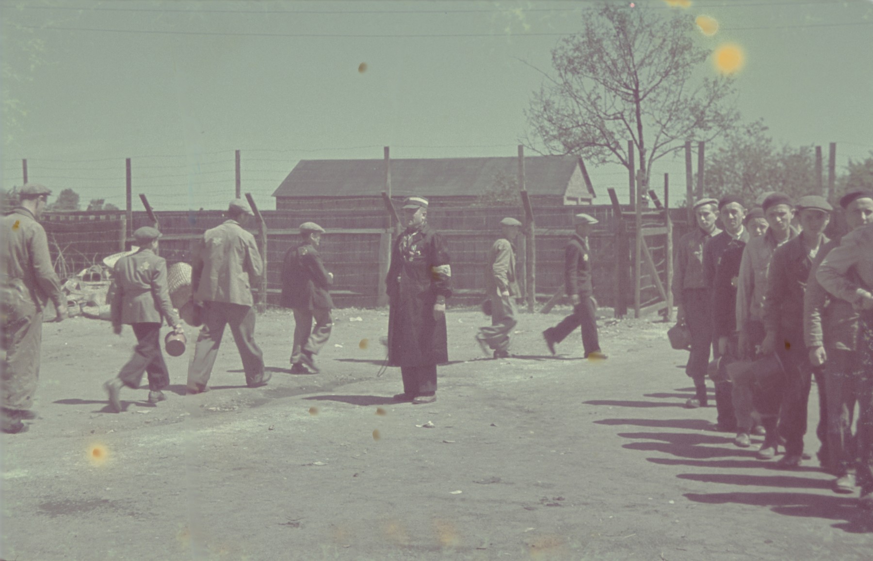 Workers line up with their lunch buckets on the supervision of a Jewish policeman in the Lodz ghetto.

Original German caption: "Rationier, Mittagsessen" (lunch rations).