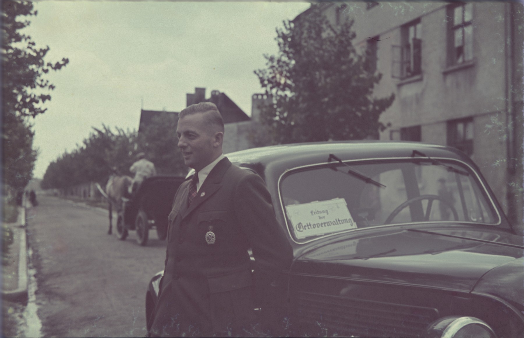 Hans Biebow, the Nazi administrator of  the Lodz ghetto,  poses in front of a car in the Lodz ghetto.

Original German caption: "Herr Biebow" (Mr. Biebow), #155.