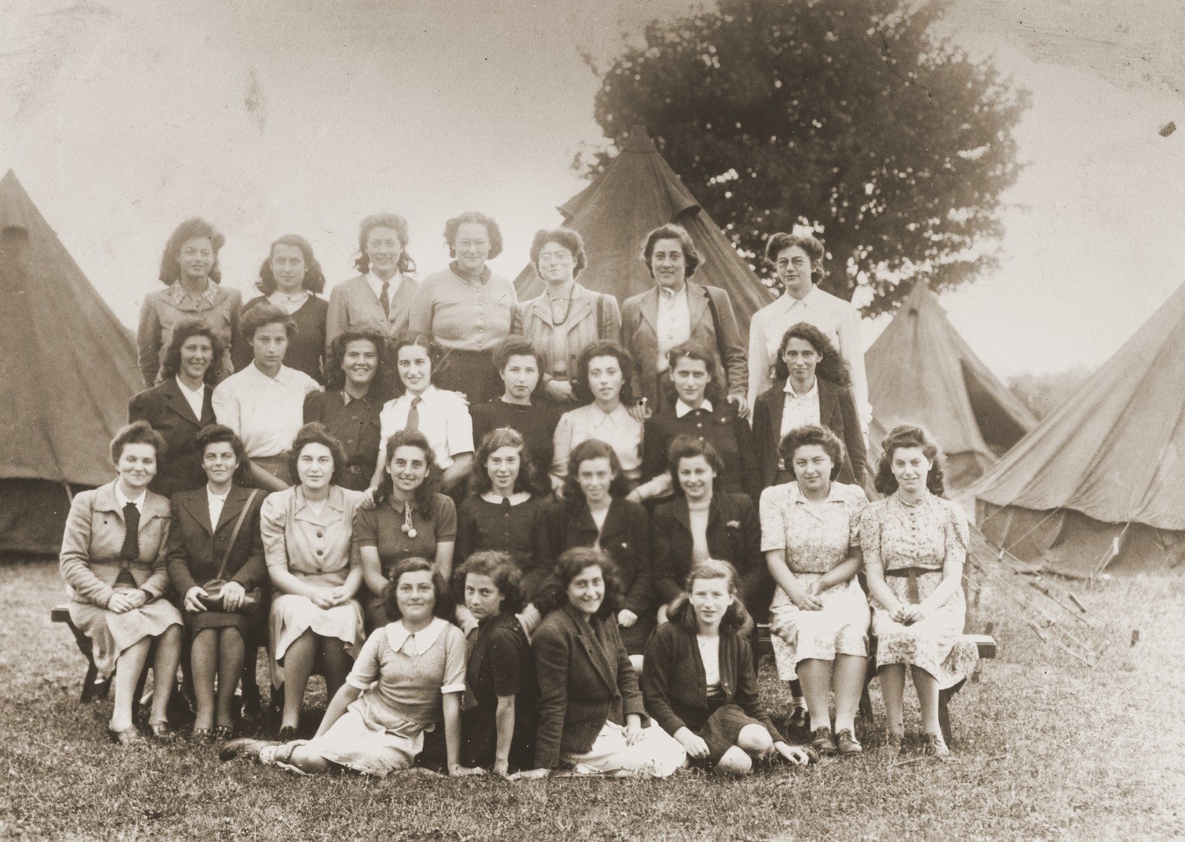 Group portrait of members of the Ezra youth movement in a "harvesting camp" outside of London, where they assisted local farmers.  

Most of the girls are German Jews who came to England on the Kindertransport.  Trudel Farntrog is pictured in the back row on the right.

.