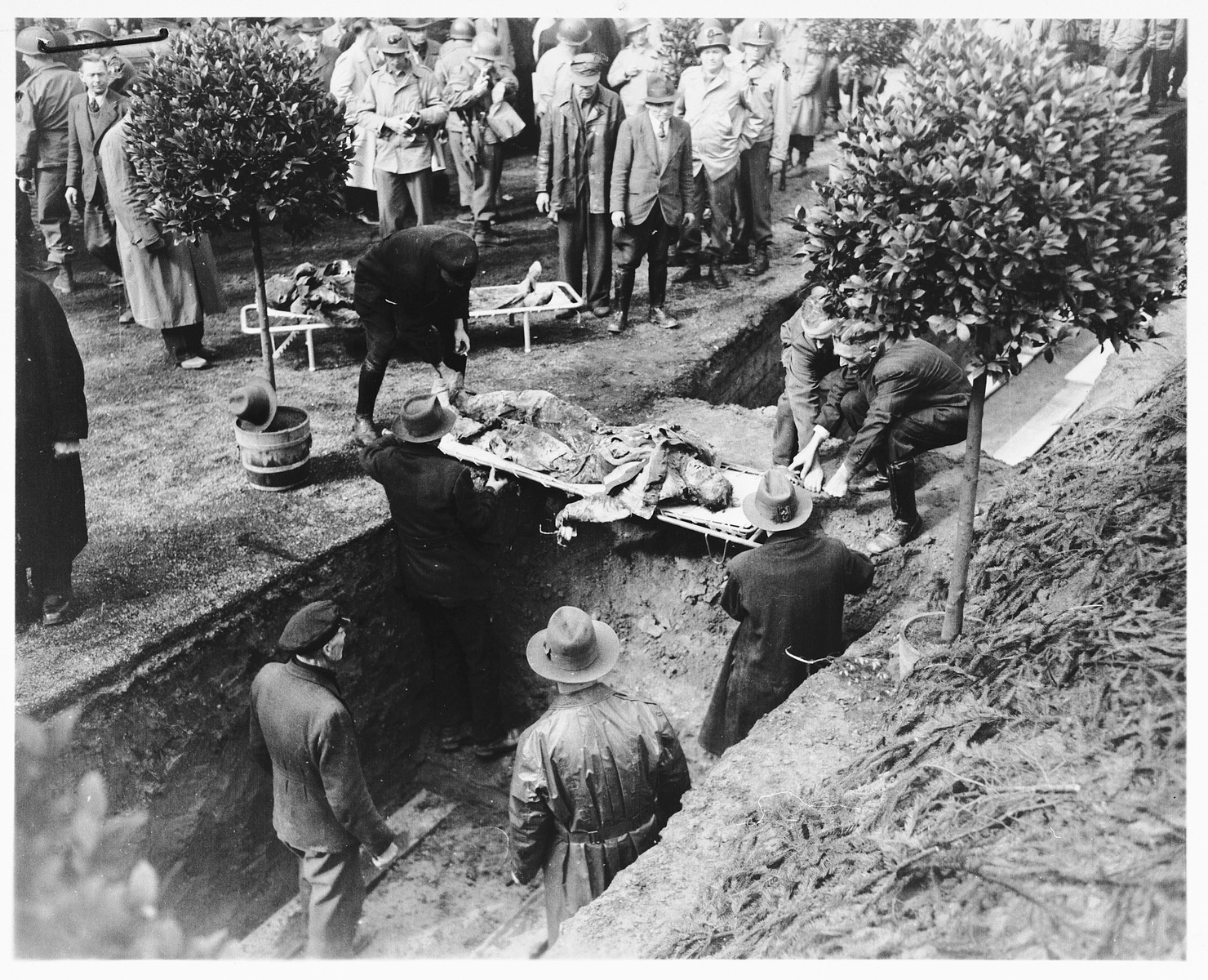 Under the direction of American soldiers, German civilians rebury the bodies of 71 political prisoners, exhumed from a mass grave near Solingen-Ohligs, in front of the city hall.  

The victims, most of whom were taken from Luettringhausen prison, were shot and buried by the Gestapo following orders to eliminate all Reich enemies just before the end of the war.
