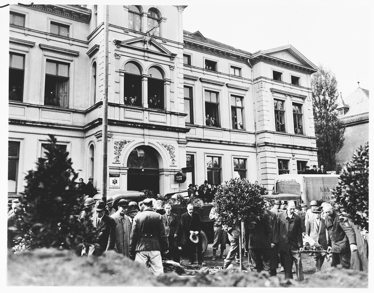 Under the direction of American soldiers, German civilians rebury the bodies of 71 political prisoners, exhumed from a mass grave near Solingen-Ohligs, in front of the city hall.  

The victims, most of whom were taken from Luettringhausen prison, were shot and buried by the Gestapo following orders to eliminate all Reich enemies just before the end of the war.