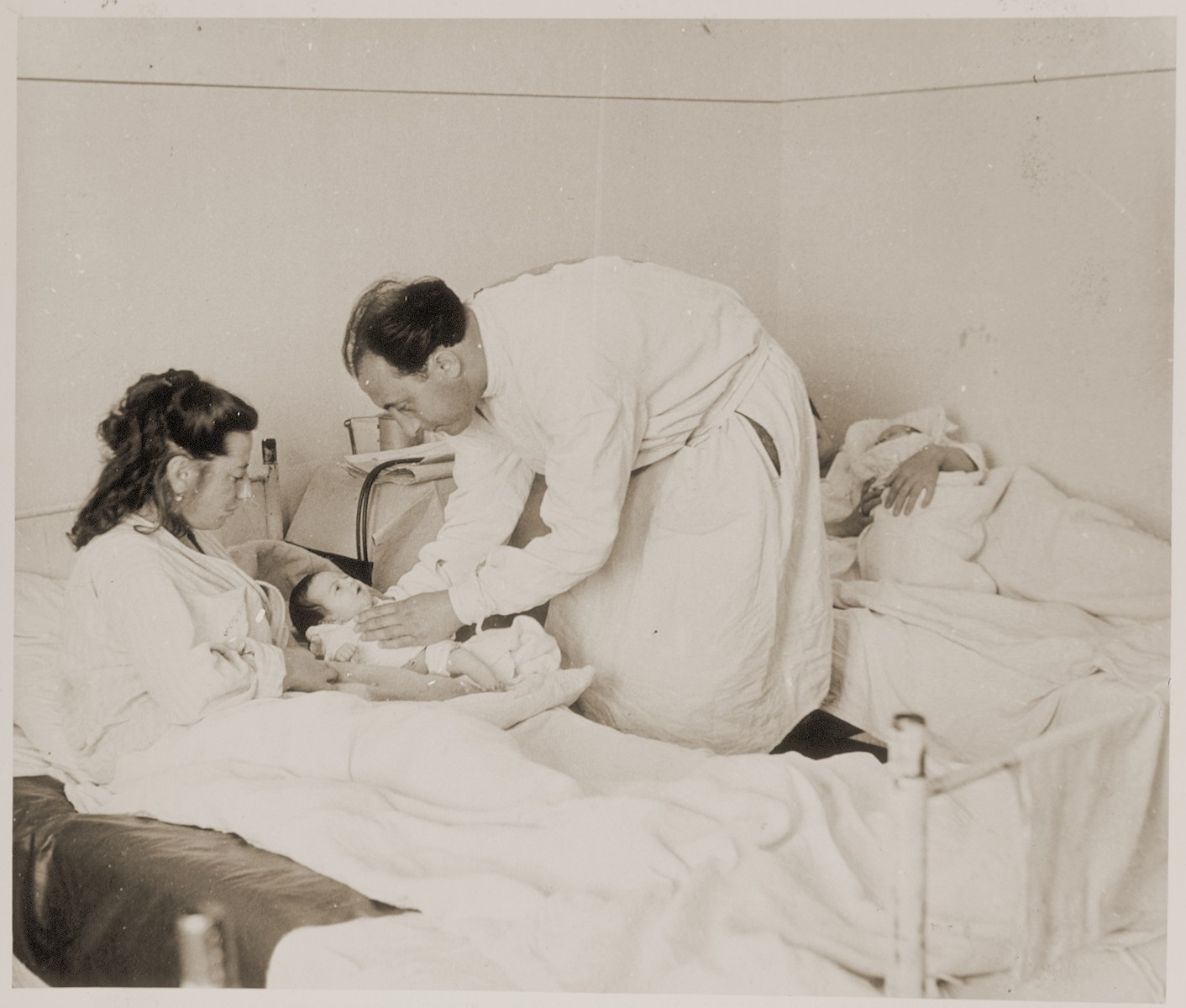 A doctor examines a newborn infant in the maternity ward of a hospital in Sankt Marien, Austria. 

Family album bearing the title "Motoring/Jewish DP camp/St. Marein [Sankt Marien]/School," that belonged to Moritz Friedler.  In 1946 and 1947, he served as a social worker with the Jewish Committee for Relief Abroad at the Sankt Marien DP camp in the British zone of Austria. Friedler subsequently became the JDC's Area Director in Linz, Austria.  The photo album documents Jewish DP life in both places.