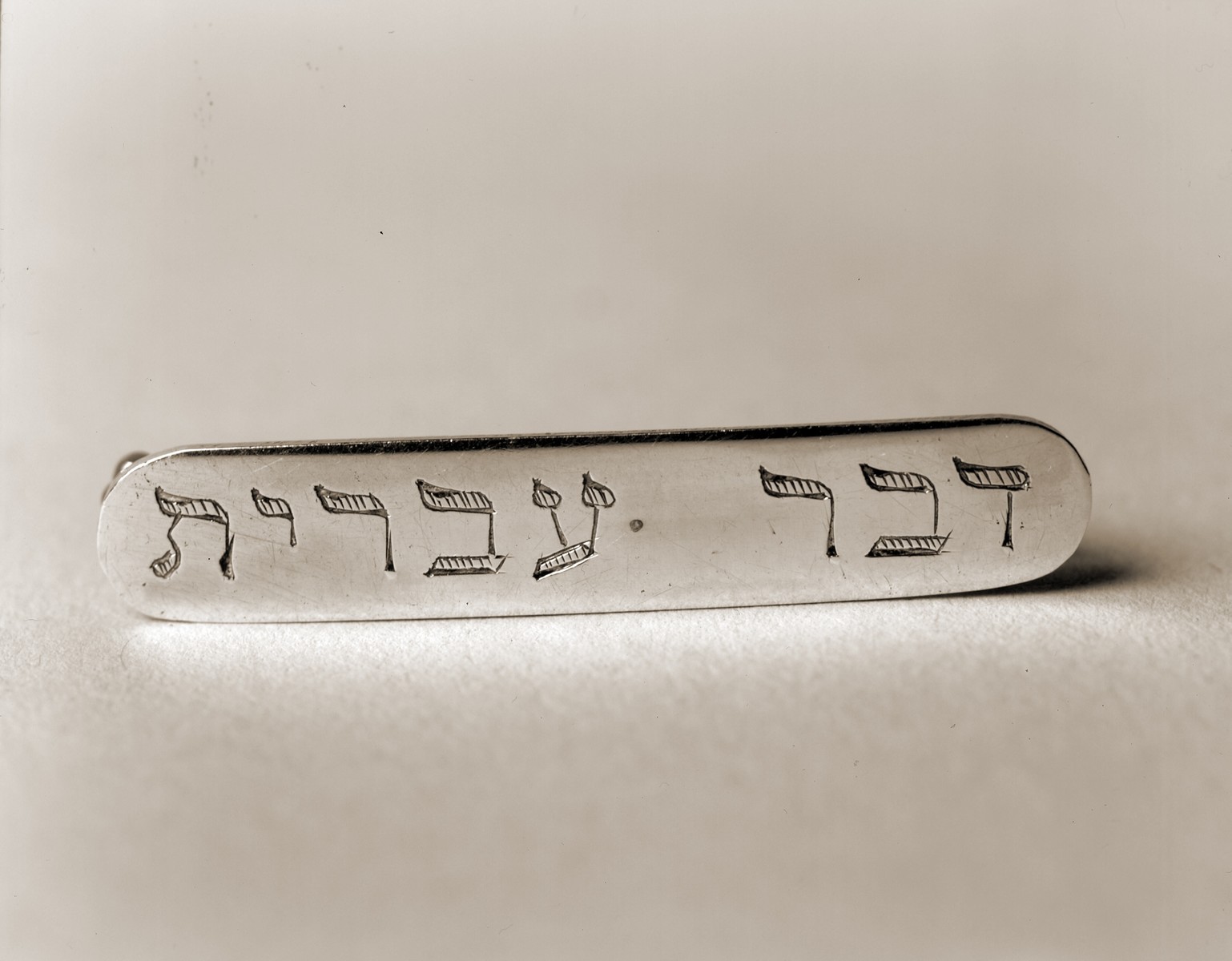Silver pin from the Schlachtensee displaced persons camp, with the Hebrew inscription "Speak Hebrew."