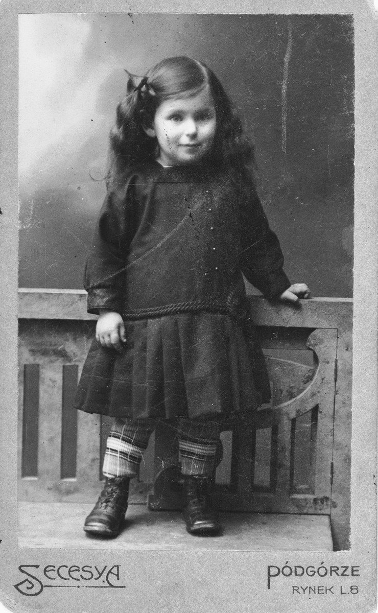 Studio portrait of Felicja Pleszowski as a young girl.

This photograph was part of an album that was saved and retrieved in the following manner.  After the war, Felicja was standing on a street corner in Krakow waiting for a bus.  A total stranger approached her and told her that she recognized her from her photographs.  The Polish woman had moved into the Klopholcz's apartment and found Felicja's photo album and autograph book from school.  The Polish woman had saved the two albums and after bumping into Felicja by pure chance, she returned the books to her.