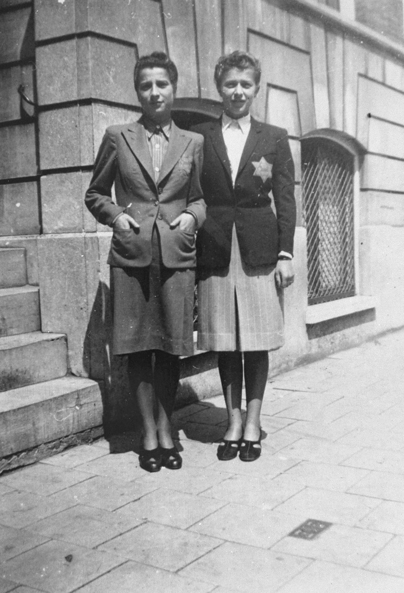 Two sisters, Jetty and Shelly de Leeuw, pose on the street wearing Jewish badges in the Jewish quarter of Amsterdam.  Both were later deported and perished in concentration camps.