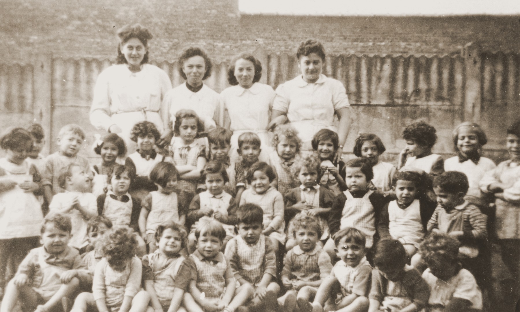 Group portrait of the children and staff of La Pouponniere children's home in Uccle.

Among those picutred in the first row is Sylvain Borisewitz.

Among thos pictuted in the first row is Sylvain Borisewitz (fifth from the left).

Pictured in the second row (4th, 3rd, and 2nd from the right) are Paula Bucholc, Jeannette Schindelheim (Oselka-Korn), and DeeDee (Edith Richter).

Pictured in the third row are Sarah Buchholc (later Suzy Eliya, sixth from the right) and Bernard Baron (now Bill Frankenstein, seventh from the right).