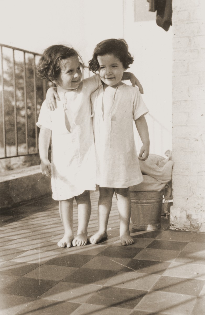 Two young girls stand on the balcony of the Home des Moineaux (AIVG)  in Uccle, Belgium

Pictured are Edith Richter and Jeannette Schindelheim (Oselka-Korn). Edith and Jeannette lived in the Baron de Castro home in Etterbeek, Brussels Belgium during the war. They were transferred to the children's home in Uccle in February 1945.