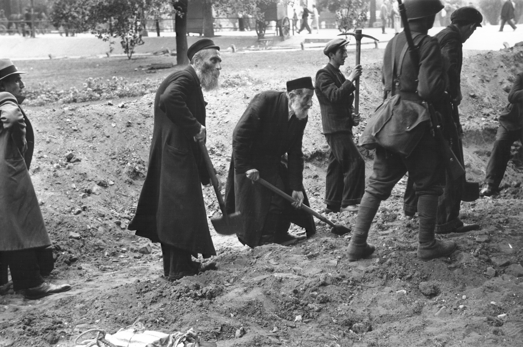 Under the supervision of Polish soldiers, elderly religious Jews dig anti-tank trenches to impede the German invasion.