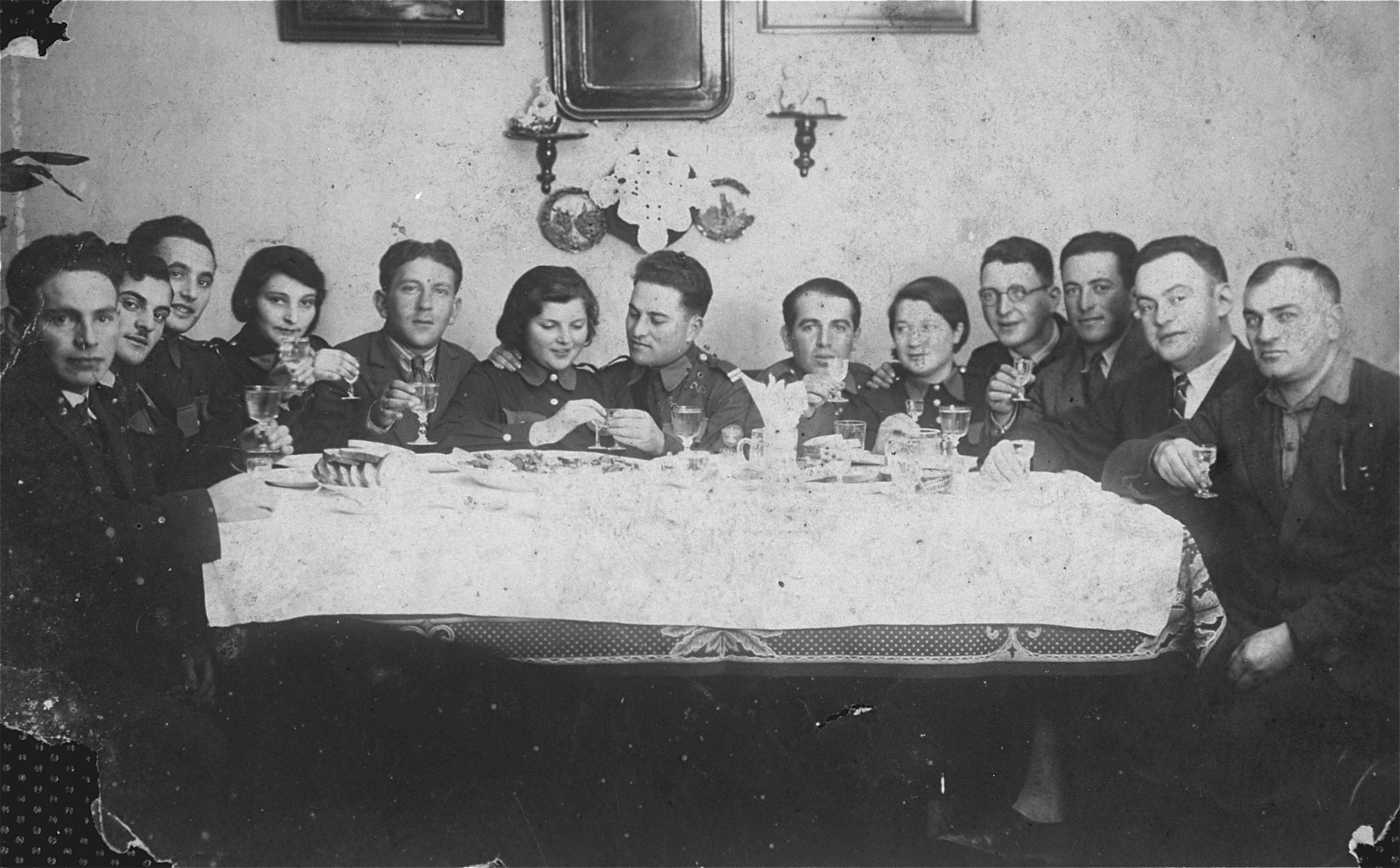 Members of Betar presidium in Sejny gather around at a  reception. 

Pictured left to right are Meyerowitz (the watchmaker and goldsmith of Sejny), Mones Shternberg, Furmanski, Tzipi Shvartz (daughter of the cantor), unidentified, Libe Lavertovitz (married a doctor from Paris and survived the war there), Yakov Ostrov (representative of Betar movement), Yehuda Edlin, Leah Neuerman, Zaidka Shvartz (violinist), Volf Ostrow, Moshe Miszkinski, and Peretz.