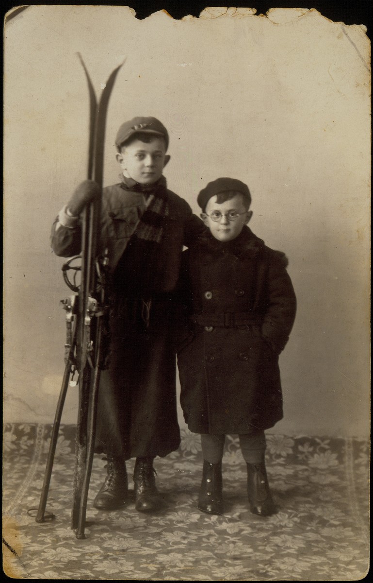 Studio portrait of two Jewish brothers, one holding a pair of skis.

Pictured are Benyamin (left) and Shmuel Sonenson in 1938. Both were killed by the Germans in the September 1941 mass shooting action in Eisiskes.