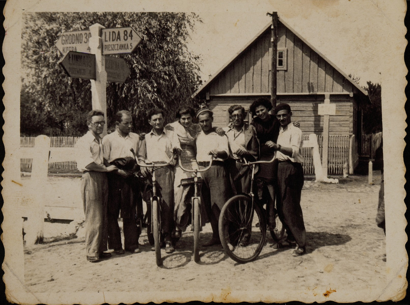 Winners of a bicycle race sponsored by local Zionist groups pose with their bicycles, next to a road sign in the village of Skidel.

Among those pictured is Shabbtai (Shepske) Sonenson (third from the left), who represented the Betar organization in Eisiskes.  Shepske was killed by the Germans during the September 1941 mass shooting action in Eisiskes.
