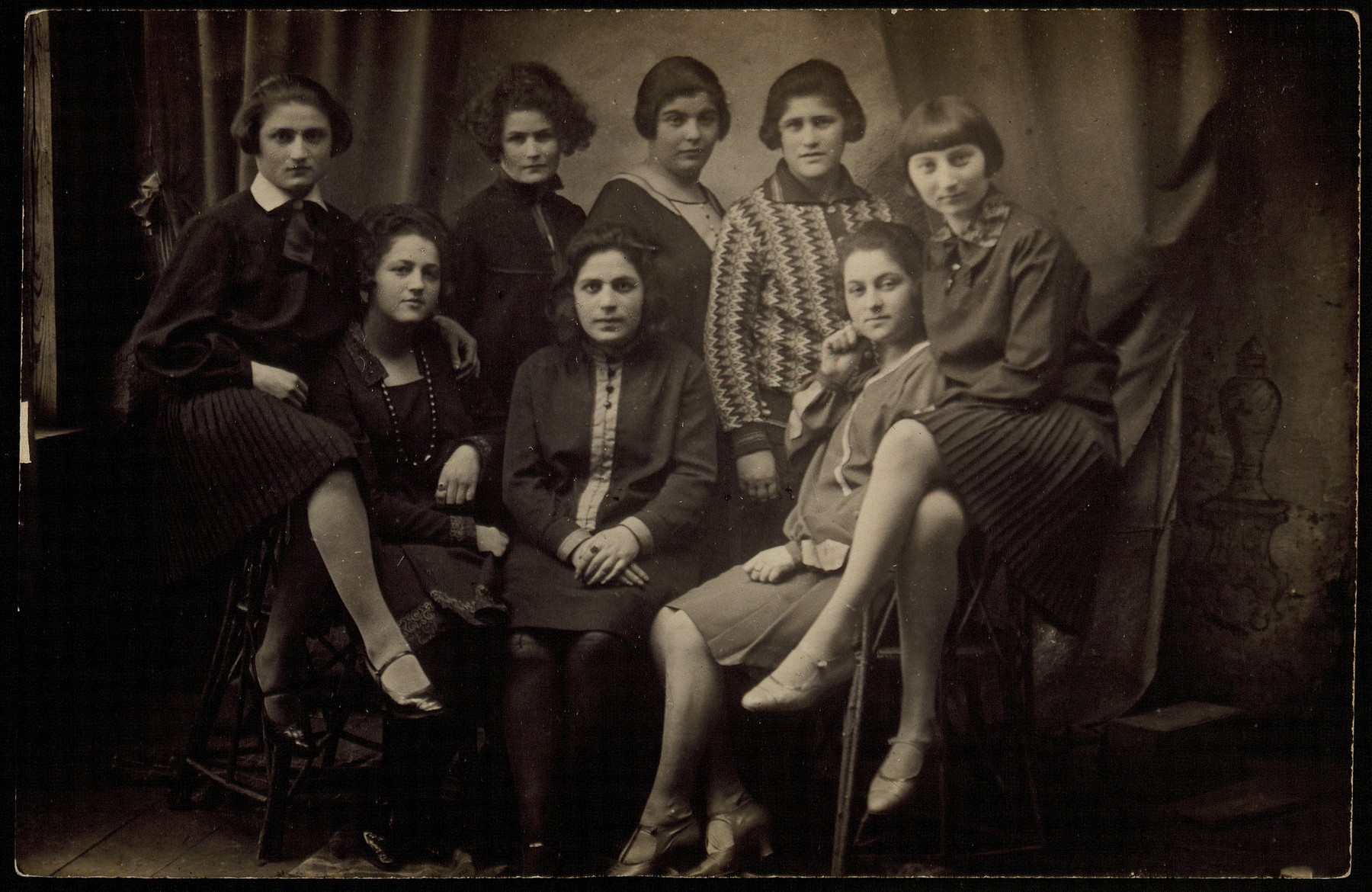 Group portrait of young Jewish women who were members of the "Club 21" in Eisiskes.

Among those pictured are Zipporah Katz (seated on the right), Kumin (second from the right), Etele Yuranski (fourth from the right), Geneshe Kaganowicz (far left) and Matle Sonenson (second from the left).  Zipporah, Geneshe and Matle later became sisters-in-law.  Matle survived the war in Siberia; Etele was killed in the Radun ghetto on May 10, 1942; Kumin died in Auschwitz; Zipporah was killed by members of the Polish Home Army in October 1944.  The others were killed by the Germans during the September 1941 mass shooting action in Eisiskes.