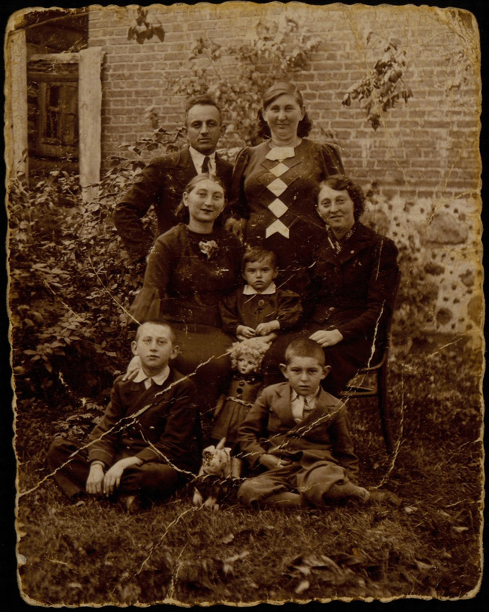 Members of the Katz and Sonenson families pose in the backyard of Alte Katz's house.  

Standing Alte Katz with her son-in-law Moshe Sonenson; (sitting on chairs, right to left) Shoshana Katz, Yaffa Sonenson with her doll and stuffed animal, and Zipporah Katz Sonenson, Yaffa's mother; (sitting on the ground, right to left) Yitzhak Sonenson, son of Moshe and Zipporah,and  next to him his uncle Avigdor Katz.