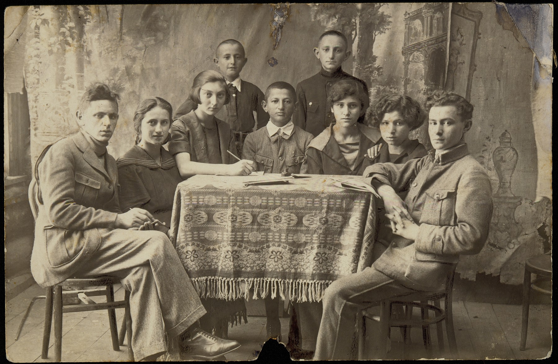 Board members of the Brenner Zionist Club and Jewish National Fund (Keren Kayemet) in Eisiskes, pose around a table.  

Among those pictured are: Peretz Kaleko (sitting at the far right), Leah Koppelman (sitting third from the right), Leibke Sonenson (sitting fourth from the right), and club secretary, Zipporah (Katz) Sonenson (fifth from the right). Peretz Kaleko and his wife Leah Koppelman immigrated to Palestine before the war.  Leibke Sonenson was killed by the Germans in the September 1941 mass shooting action in Eisiskes.