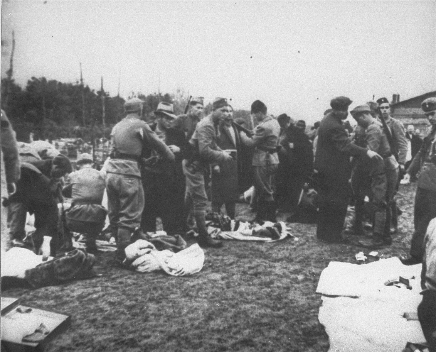 Ustasa guards in the Jasenovac concentration camp strip newly arrived prisoners of their personal possessions.

Andor Willer is pictured in the left foreground (left) in the light colored hat and dark overcoat being manhandled.  Mr. Willer perished in Jasenovac on December 25, 1944, along with his parents, brothers, and sisters.
