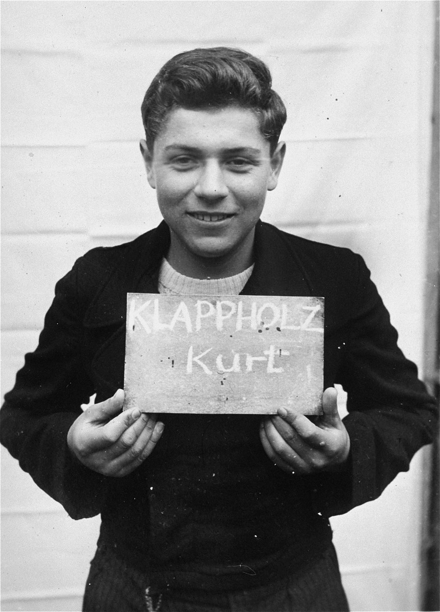 Kurt Klappholz holds a name card intended to help any of his surviving family members locate him at the Kloster Indersdorf DP camp.  This photograph was published in newspapers to facilitate reuniting the family.