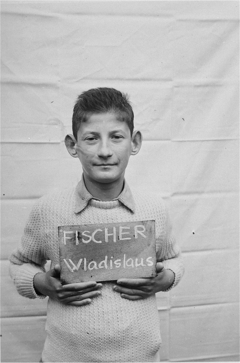 Wladislaus Fischer holds a name card intended to help any of his surviving family members locate him at the Kloster Indersdorf DP camp.  This photograph was published in newspapers to facilitate reuniting the family.