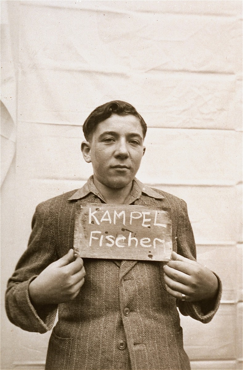 Fischer Kampel holds a name card intended to help any of his surviving family members locate him at the Kloster Indersdorf DP camp.  This photograph was published in newspapers to facilitate reuniting the family.