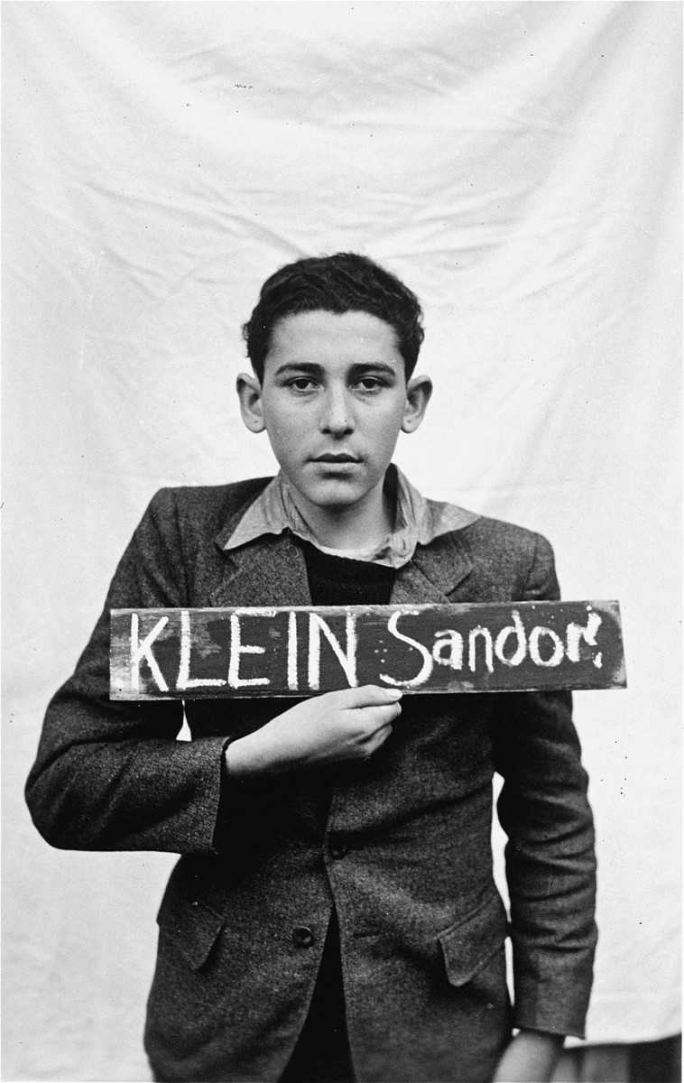 Sandor Klein holds a name card intended to help any of his surviving family members locate him at the Kloster Indersdorf DP camp.  This photograph was published in newspapers to facilitate reuniting the family.