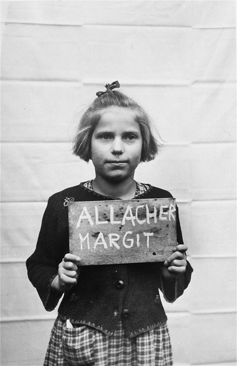 Margit Allacher holds a name card intended to help any of her surviving family members locate her at the Kloster Indersdorf DP camp.  This photograph was published in newspapers to facilitate reuniting the family.