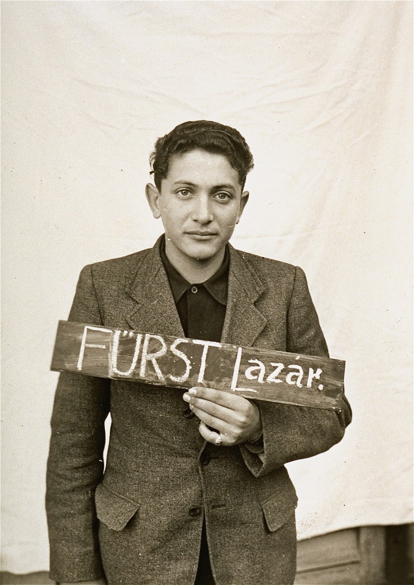 Lazar Furst holds a name card intended to help any of his surviving family members locate him at the Kloster Indersdorf DP camp.  This photograph was published in newspapers to facilitate reuniting the family.