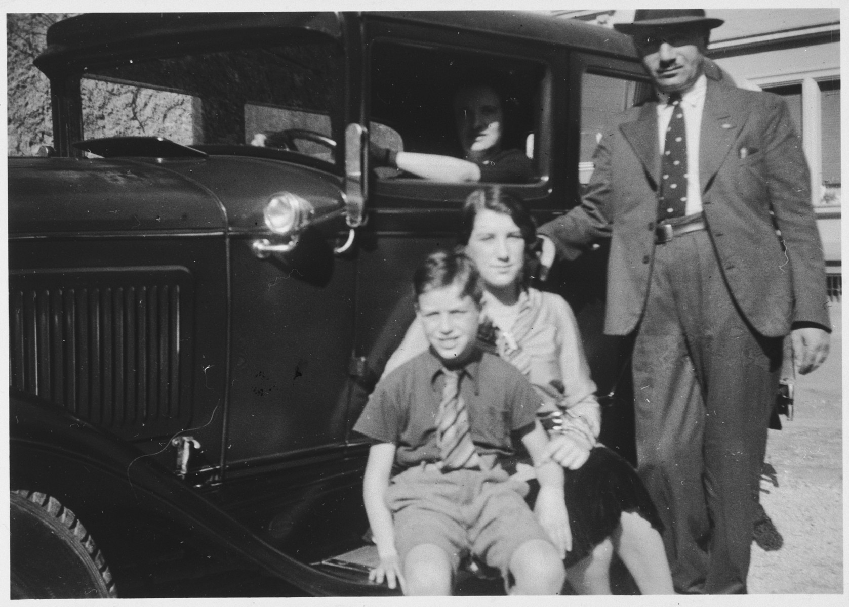 David and Paula Schwab pose in front of a car with their two children Gerd and Margot.