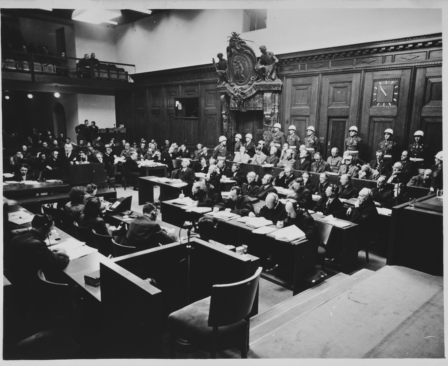 View of the courtroom during a session of the International Military Tribunal trial of war criminals at Nuremberg.

In the foreground is the witness chair.  In the background at the left, Justice Robert Jackson delivers his opening address.