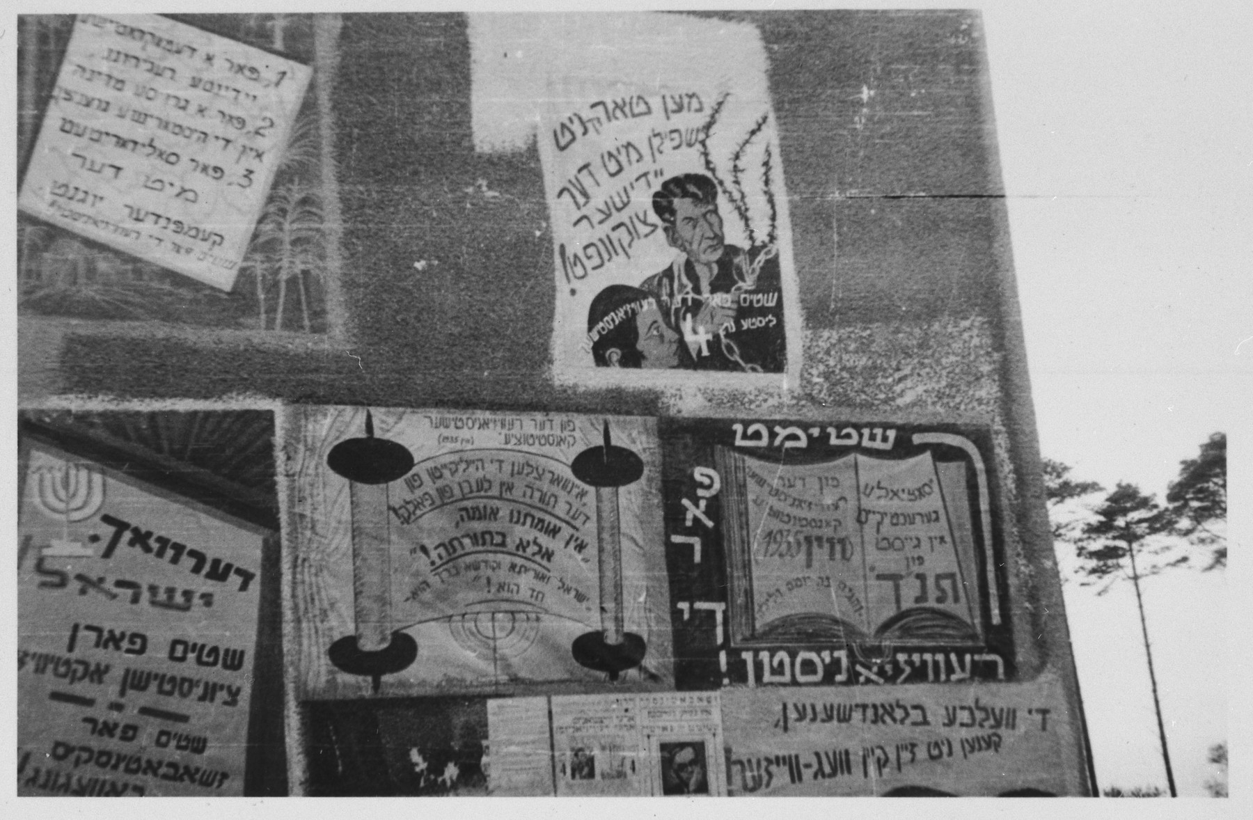Assorted election signs are posted on the outside wall of a barracks in the Bergen-Belsen displaced persons camp.