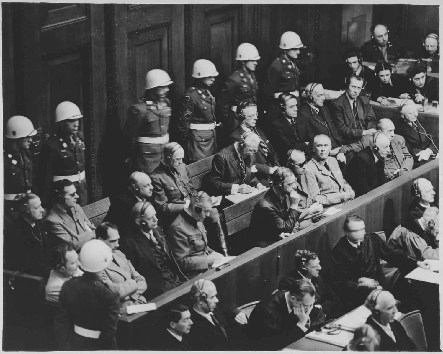 View of the defendants dock at the International Military Tribunal trial of war criminals at Nuremberg.

Seated in front of the defendants are the translators.  Mr. Walter Seligson, translation supervisor (a German Jew owho immigrated first to Palestine and then to the United States) is seated fourth from the left.