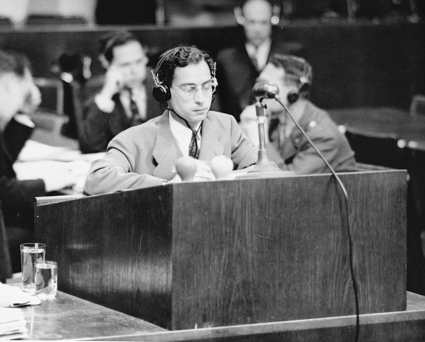 Chief Prosecutor James M. McHaney stands at the speaker's podium during the Medical Case (Doctors') Trial in Nuremberg.

Jack Robbins is seated at the table directly behind McHaney.