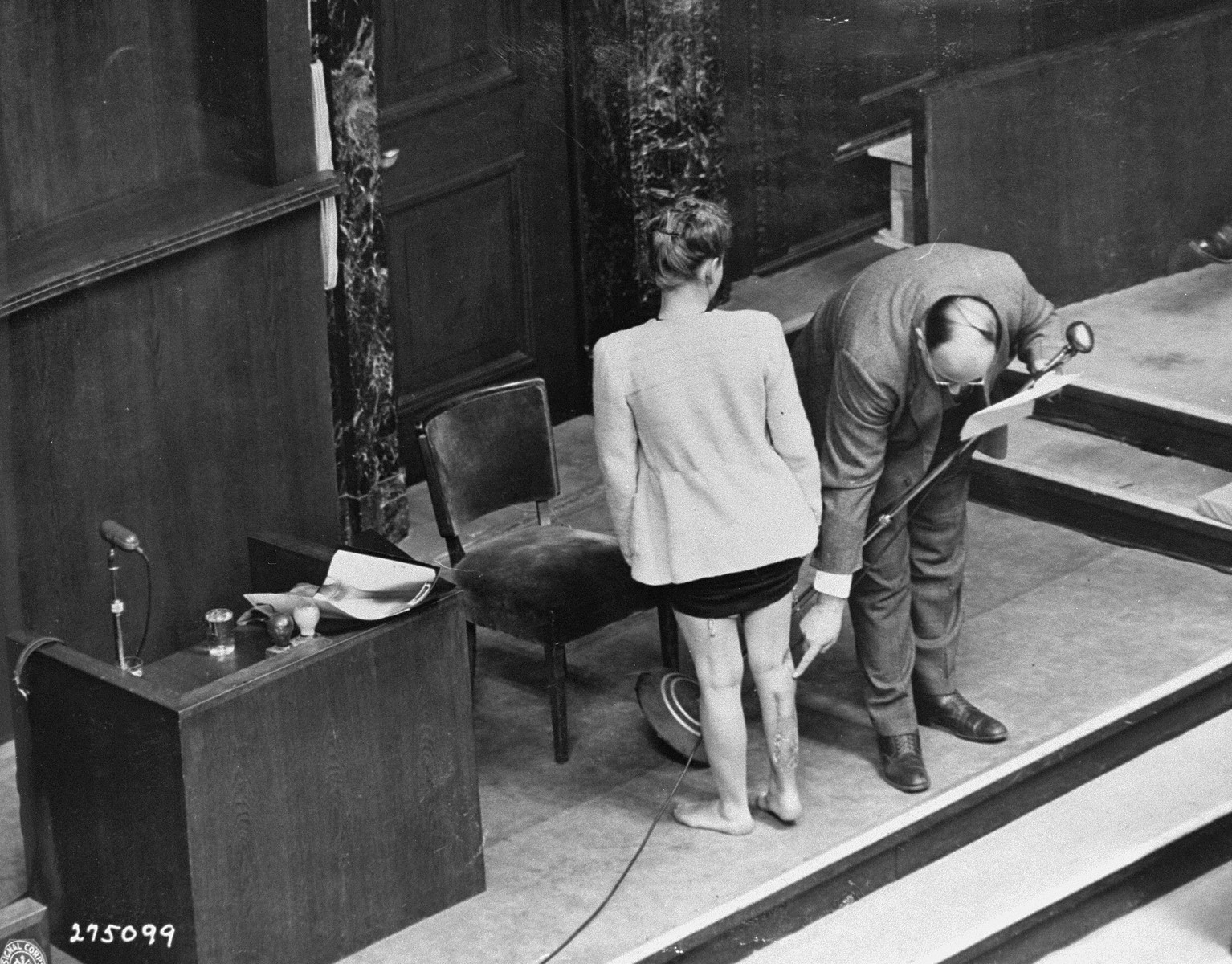 Polish survivor Jadwiga Dzido shows her scarred leg to the court, while expert witness Dr. Alexander explains the nature of the medical experiment performed on her in the Ravensbrueck concentration camp.  Dzido and Alexander were appearing as witnesses at the Doctors Trial.

The experiments were performed by defendants Herta Oberheuser and Fritz Ernst Fischer, on November 22, 1942.