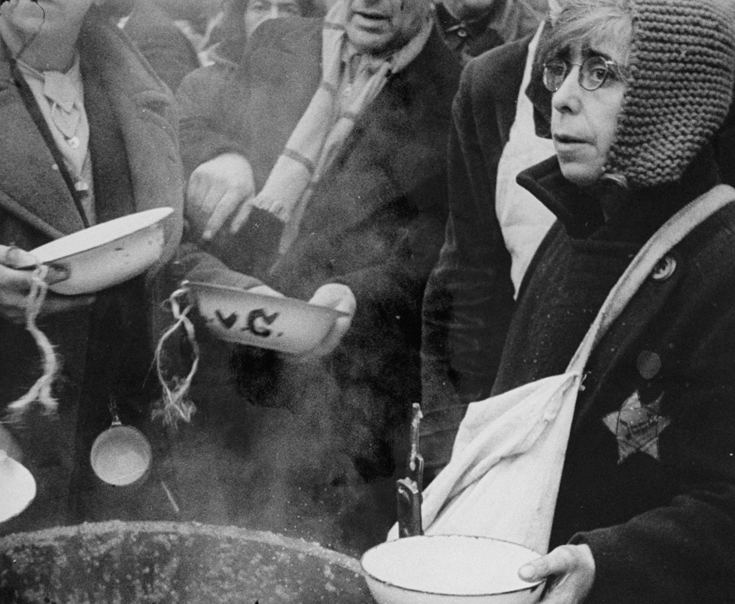 A woman who has just arrived in Theresienstadt with a transport of Dutch Jews waits to receive her bowl of  food in the courtyard of the ghetto. [oversized photo]