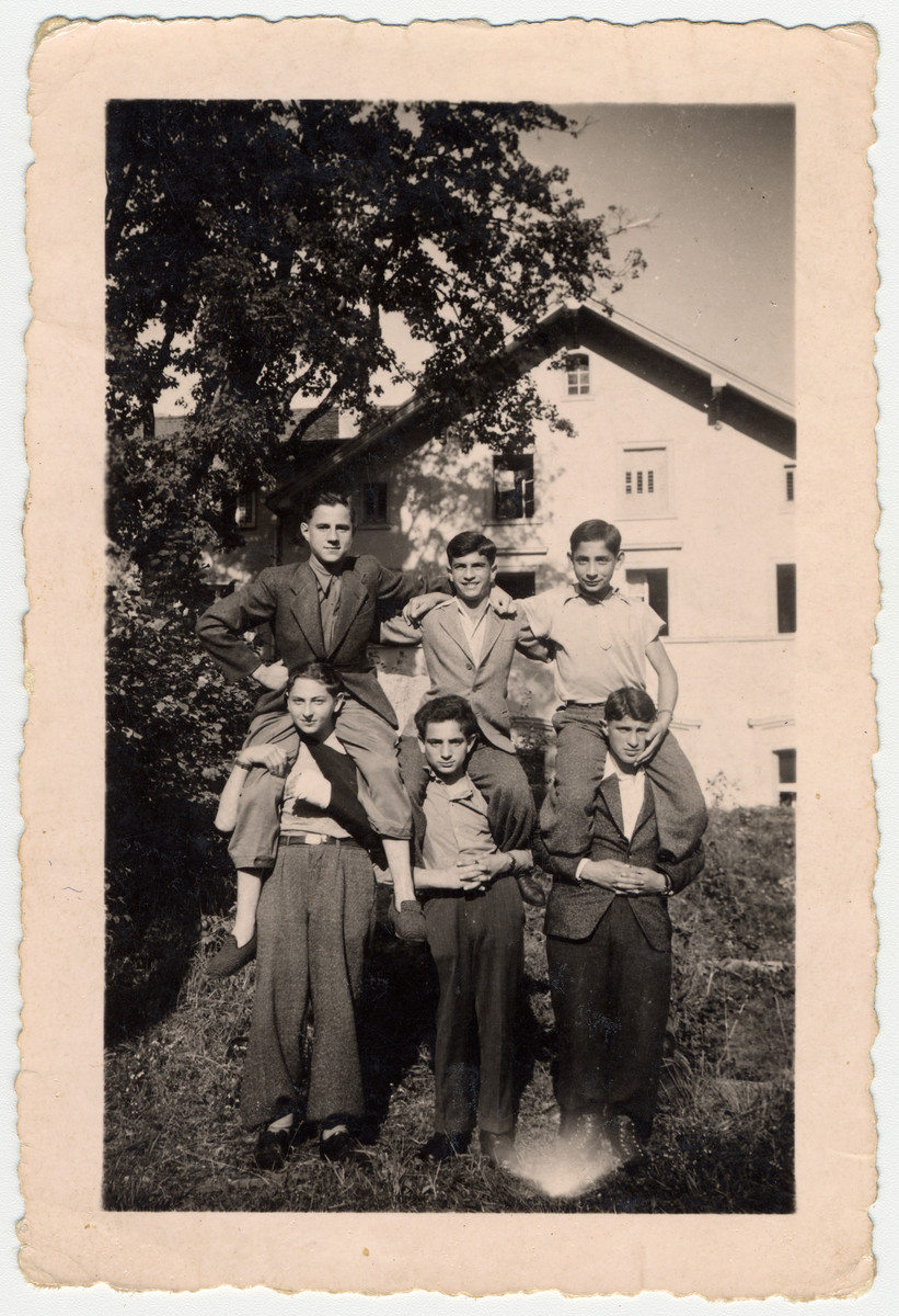 Six teenagers, among them child survivors from Buchenwald, make a human pyramid in [what probably is] the Ambloy children's home.

Among them is Szimon Mirawnik