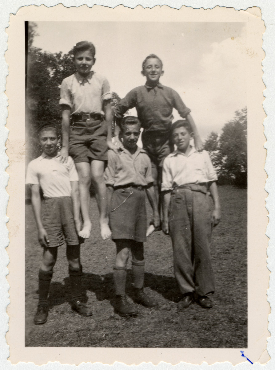 Five child survivors from Buchenwald make a human pyramid in [probably] the Ambloy children's home. 

Jacques Rybsztajn is at the bottom left.